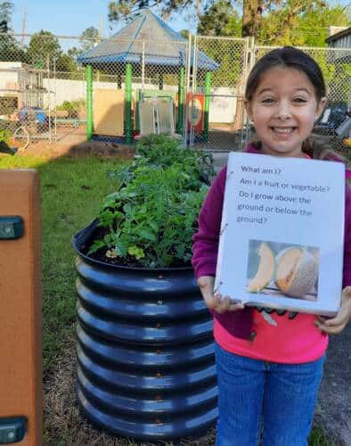 Child holding up a picture book in the garden